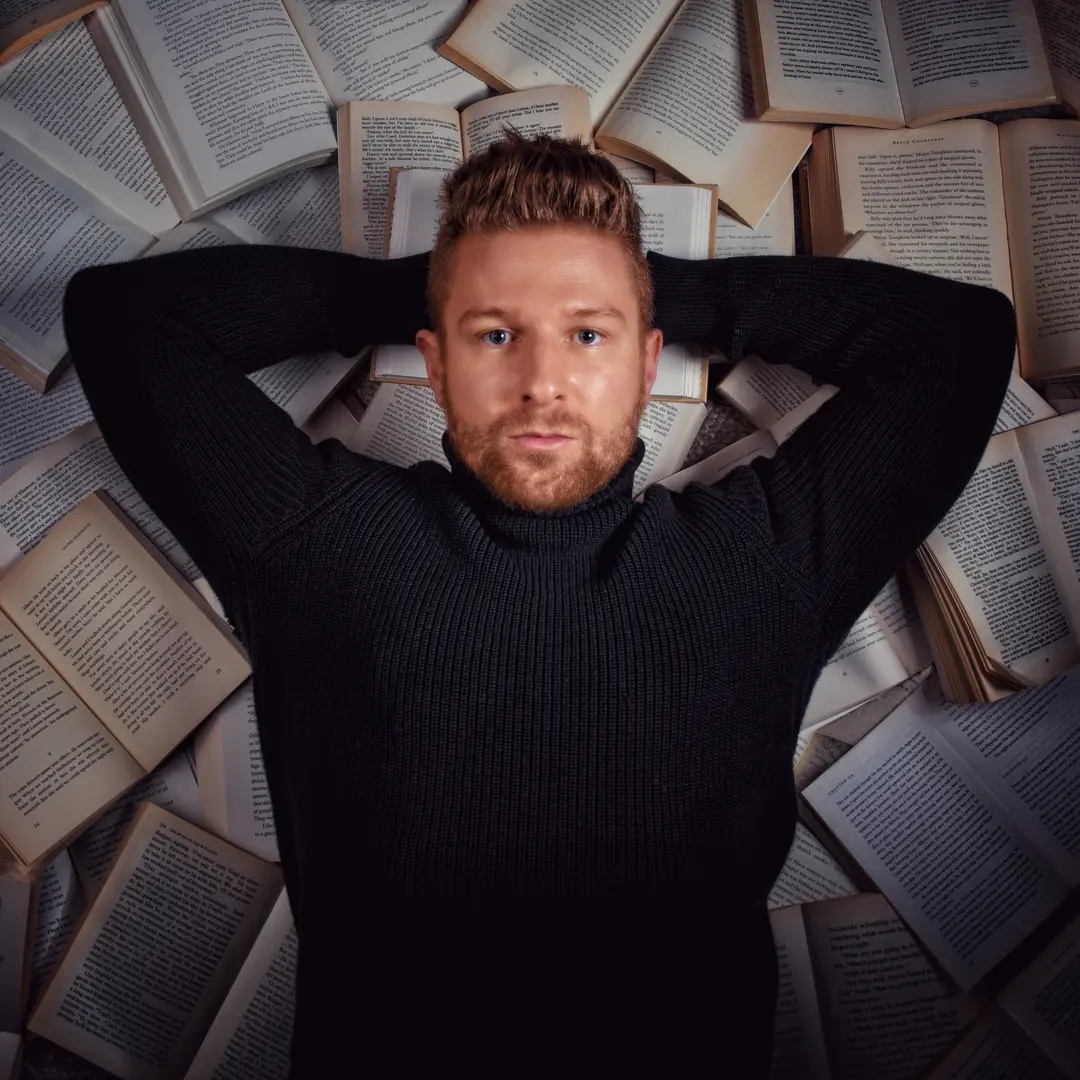 Kendall King lying amongst scattered book pages
